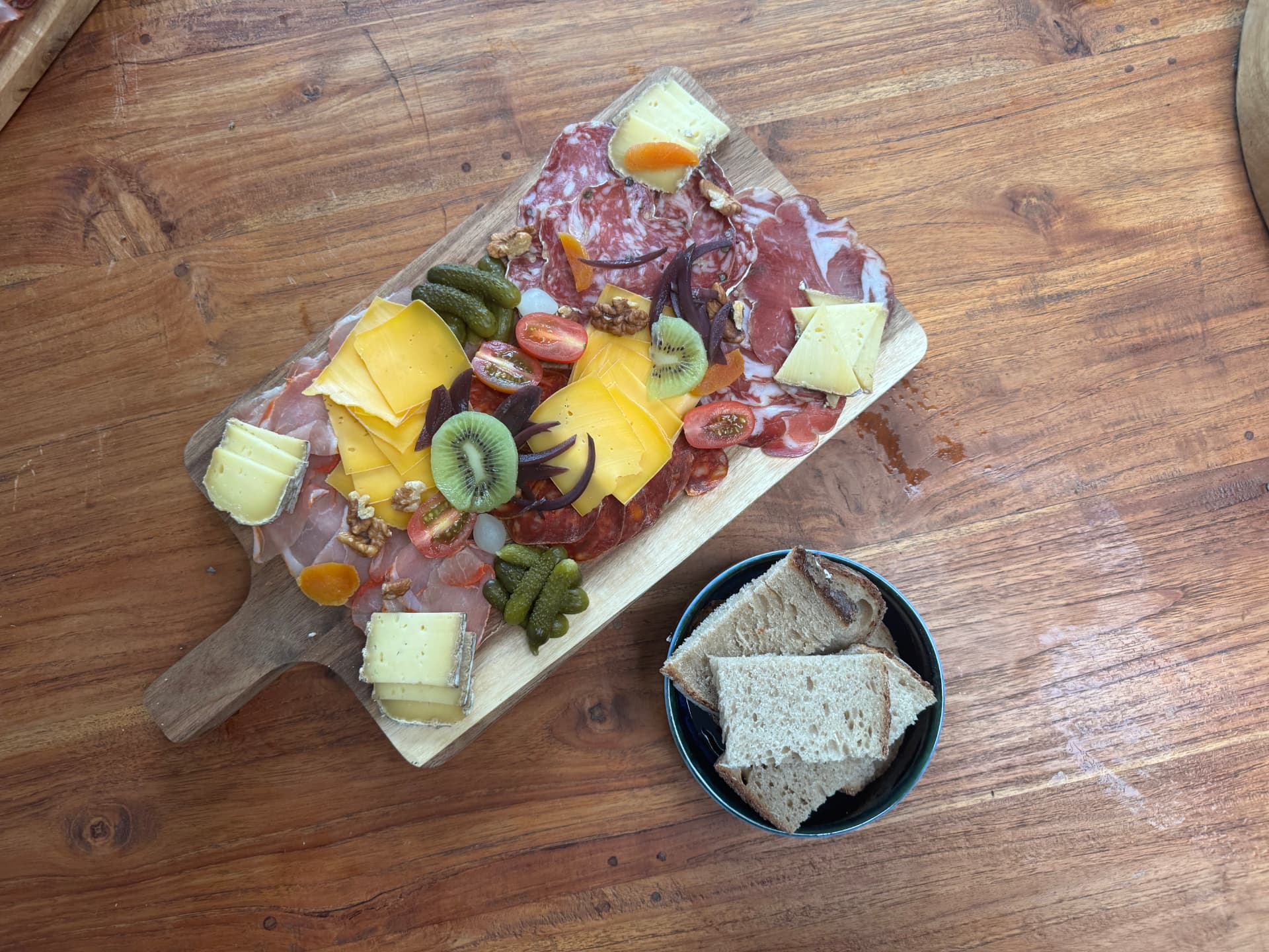 Une planche apéritive mixte fromage et charcuterie, servie avec pain et condiments
