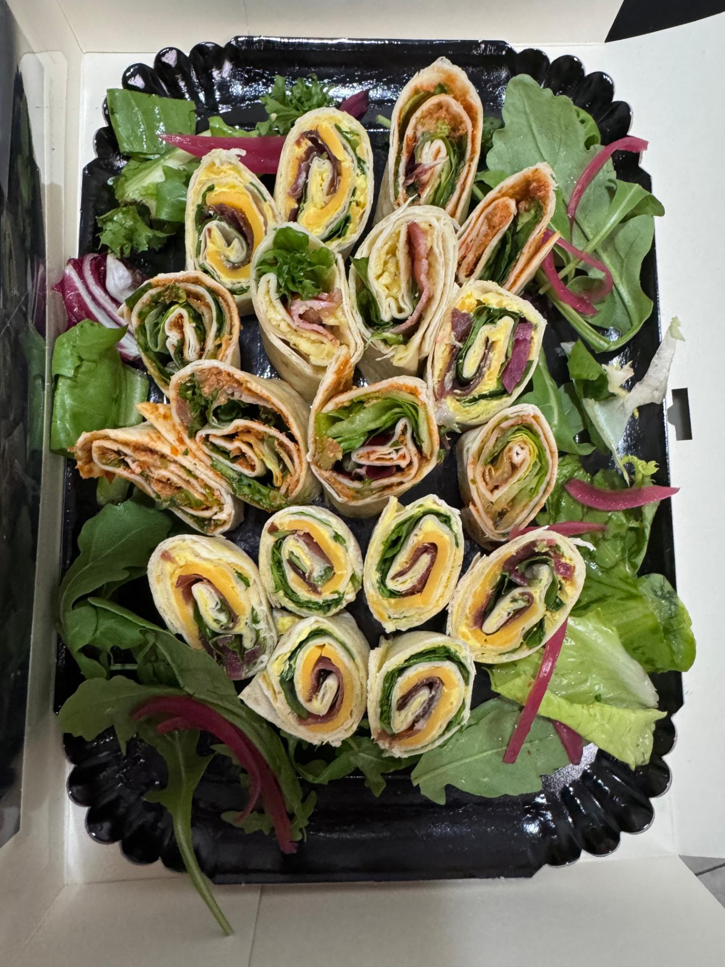 Des mini wraps colorés garnis de crudités, fromage et viandes fines, alignés en plateau