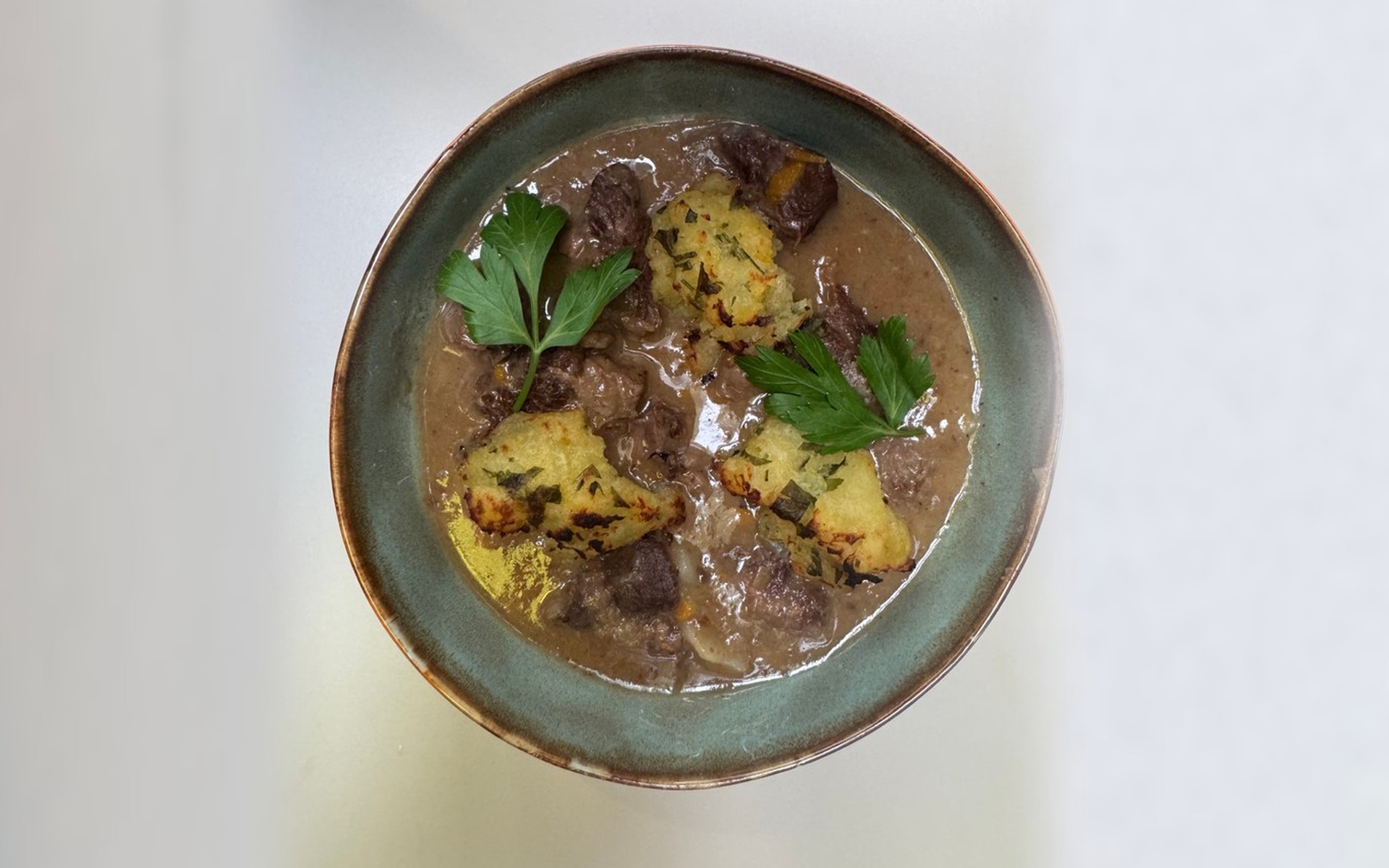 Un bol de mijoté de bœuf aux agrumes servi avec des quenelles de pommes de terre aux herbes